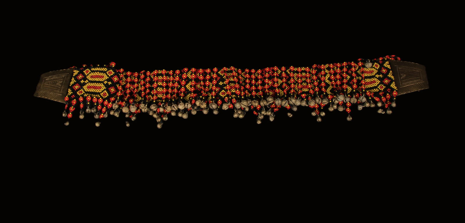 Philippines Tboli Beaded Belt: A T'boli beaded belt, with dangling bells, shells, red, black and yellow beads. Incised brass buckles. 28" L. The belt is worn by T'boli women, particularly during celebrations and festivals, and the