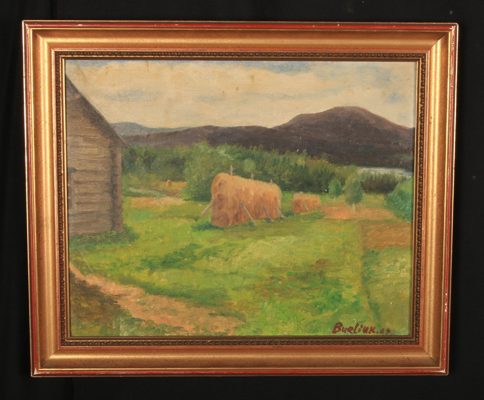 Oil Painting by David Burliuk: The painting depicts a rural landscape scene with haystacks and a corner of a barn, set against a backdrop of mountains. Signed lower left Burliuk and dated 49.