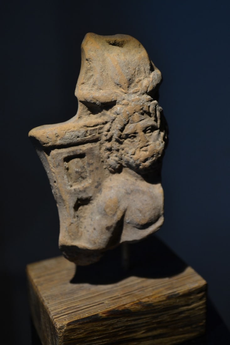 Ancient Egyptian Terracotta - Serapis: Fragmentary figure of Serapis. With thick wavy hair and thick beard. 2nd/3rd Century A.D. 3 inches high. Mounted. Old Belgian collection. Serapis was an Egyptian god whose devotees united the worship