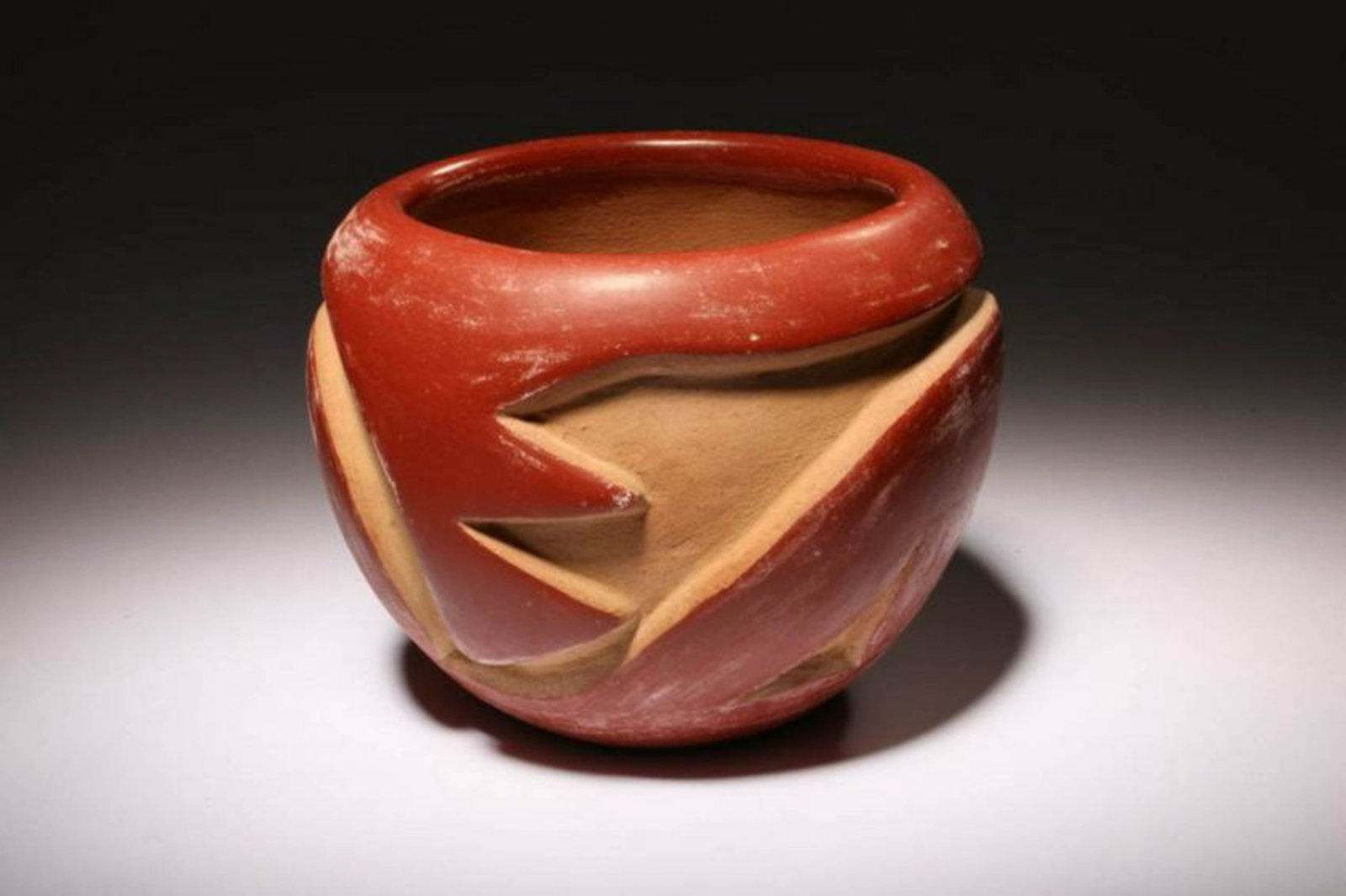 Native American Redware Bowl: Native American Redware Bowl. Deep relief abstract design. Red glaze on cream ground. Dimensions: 3-3/4" H x 4-1/2 Dia.; Weight: 1 lb. Signed on bottom, illegible
