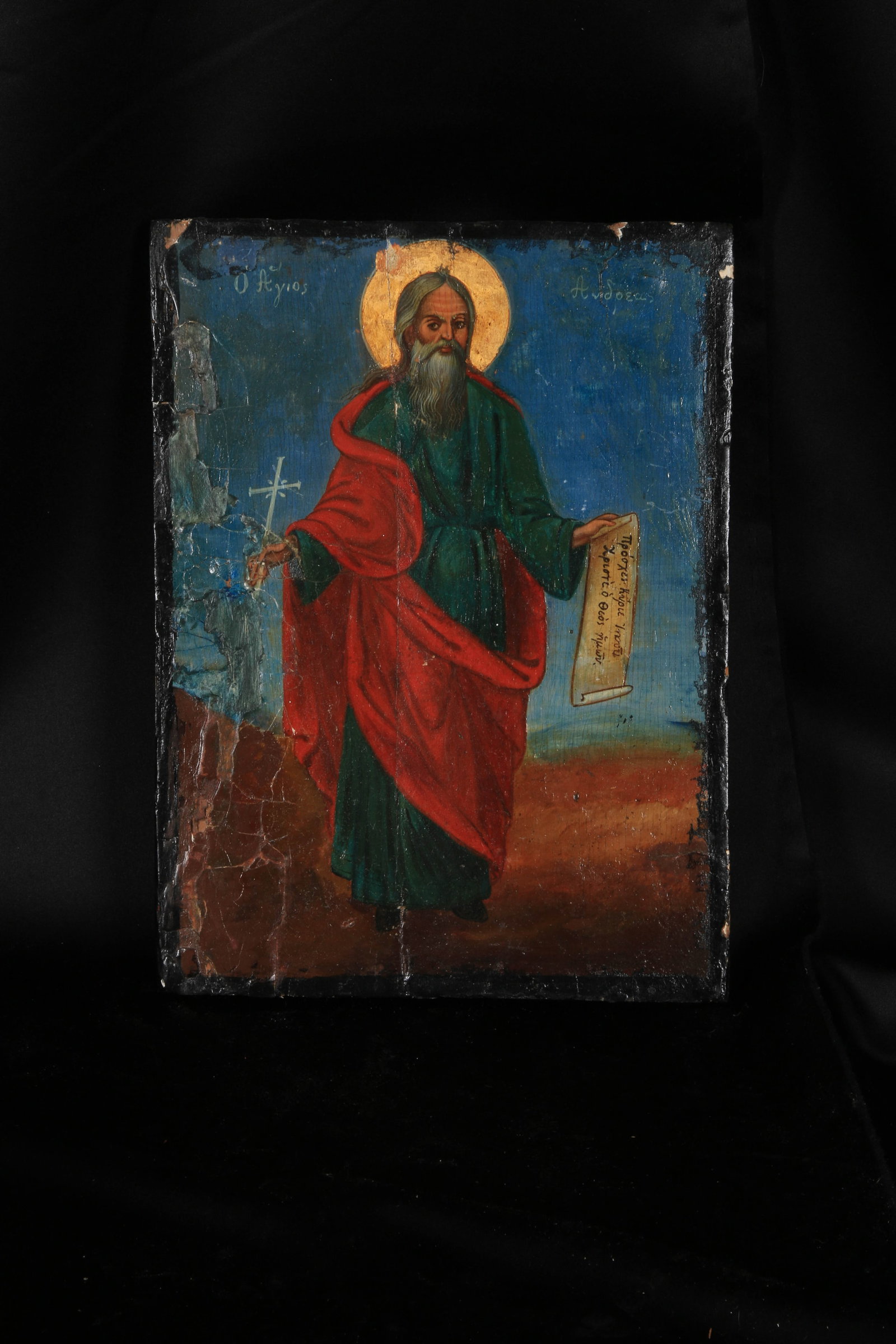 Greek Orthodox Christian Icon of Saint Andrew the Apostle.: 19th C. Greek Icon, the Saint is shown with a long grey beard, wearing the traditional green robe aad red cloak, holding a scroll in one hand and a cross in the other.The Greek text at the top left "?