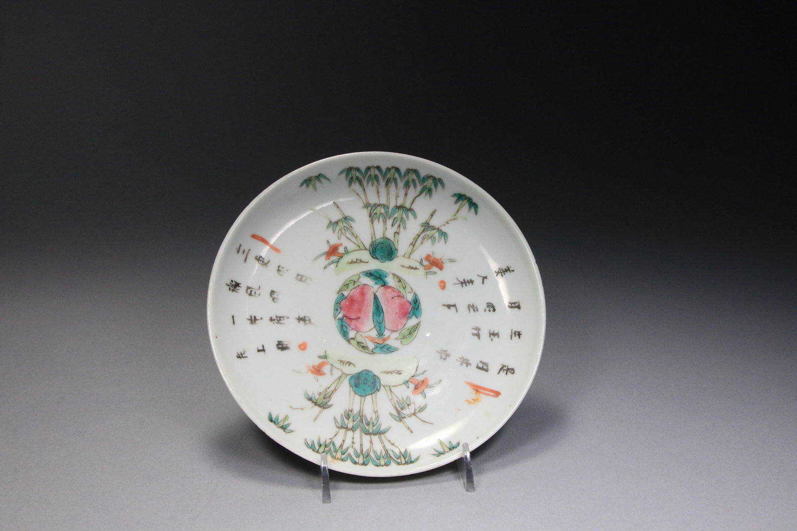 Chinese Famille Rose Porcelain Dish - 19th Century: Hand-painted enamel designs combining floral motifs with calligraphy. The center of the plate depicts peaches, a traditional Chinese symbol for longevity. Radiating from the center are lush bamboo sta