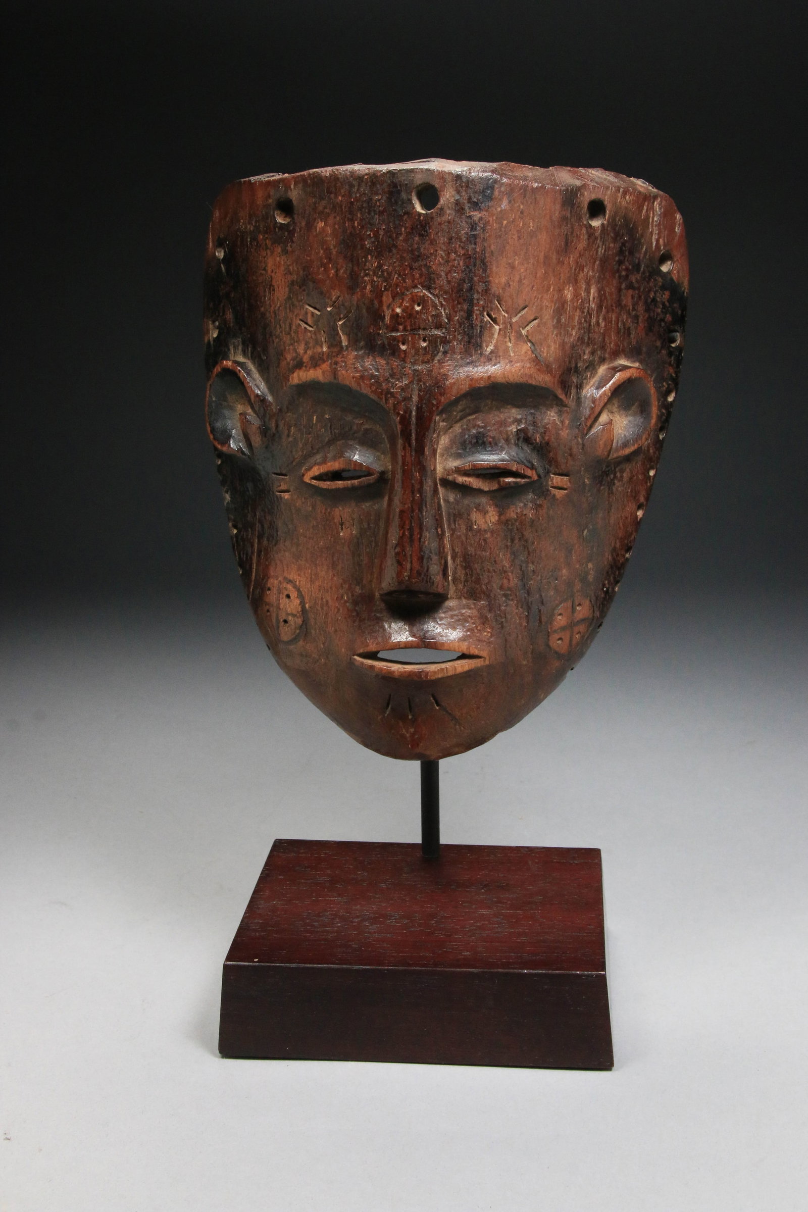 African Art Old Chokwe Mask: A very old wood Chokwe mask, Zaire, Central Africa. The mask features traditional cross scarification, C-shaped ears, almond shaped eyes, thin mouth. 6-3/4" H x 6" W. display stand is included. Proven