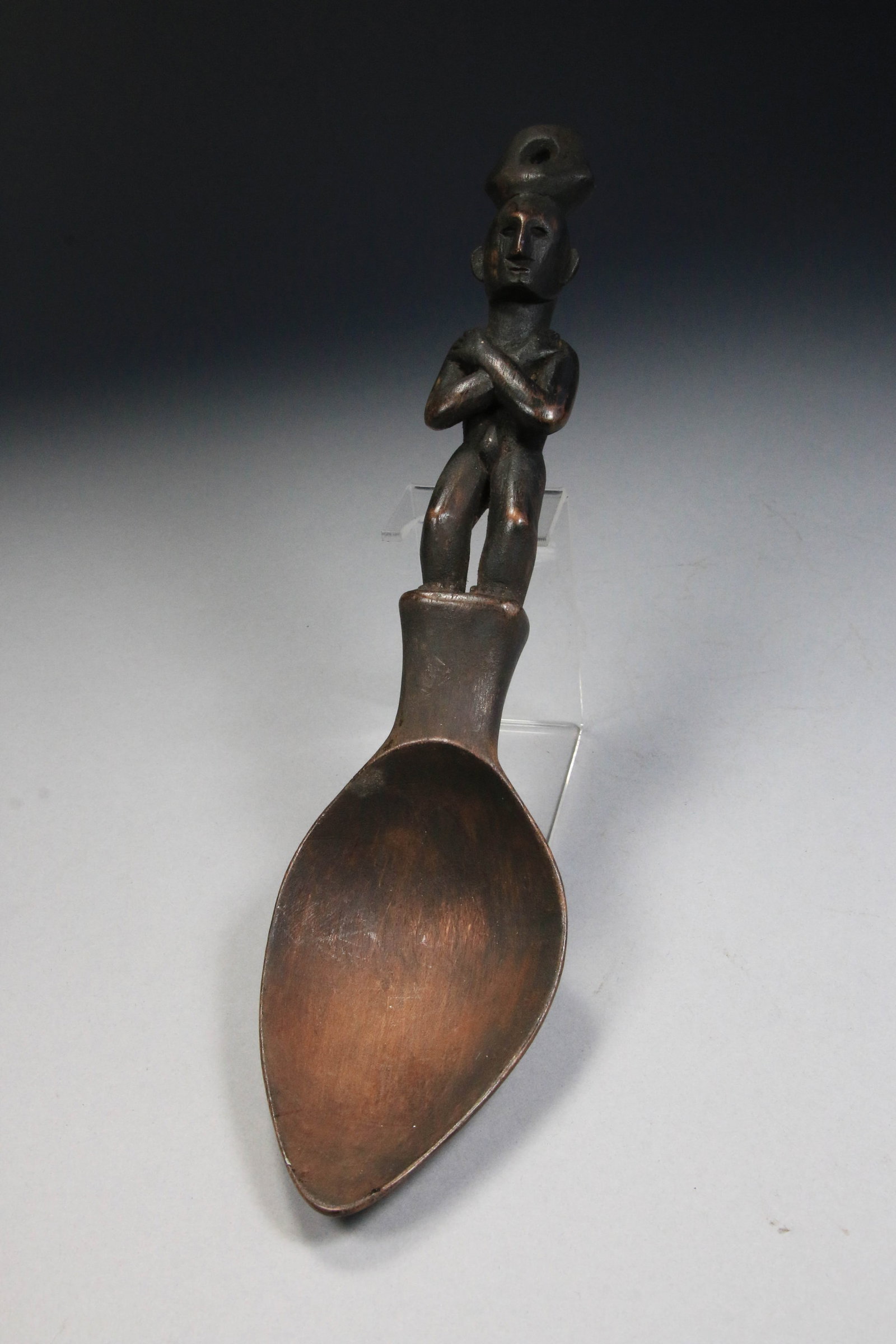 Philippines Ifugao Tribal Spoon: The handle is carved from wood in the form of a standing human figure known as a bulul or bin-nullol with arms crossed at chest, suspension hole at top, that serves as a protective guardian deity. 11"