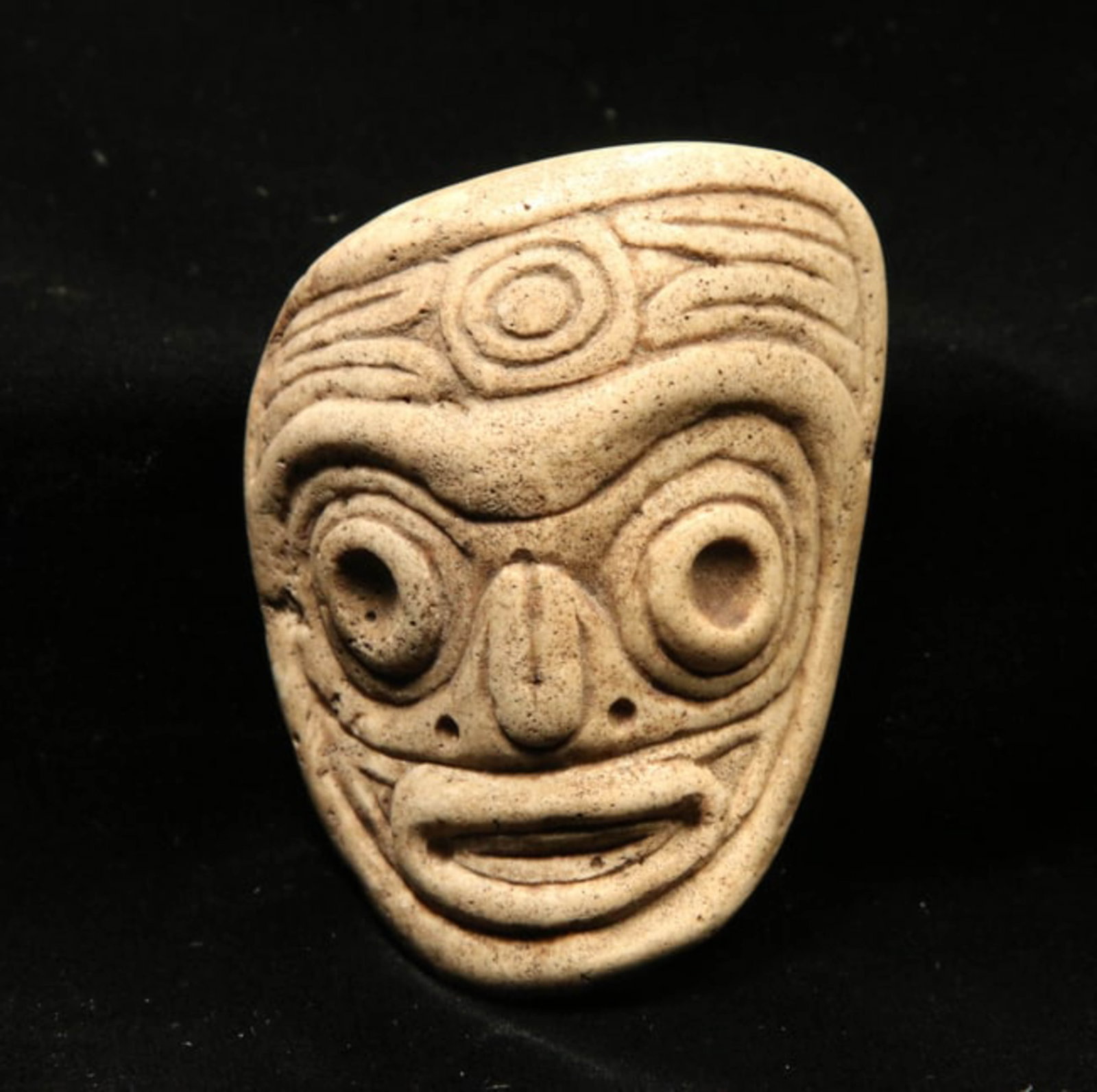 Pre-Columbian Taino Maskette: A stone maskette of a face of a Zemi, with scroll design at forehead, 3" L. Provenance: Ex collection, Tony Milton, NM