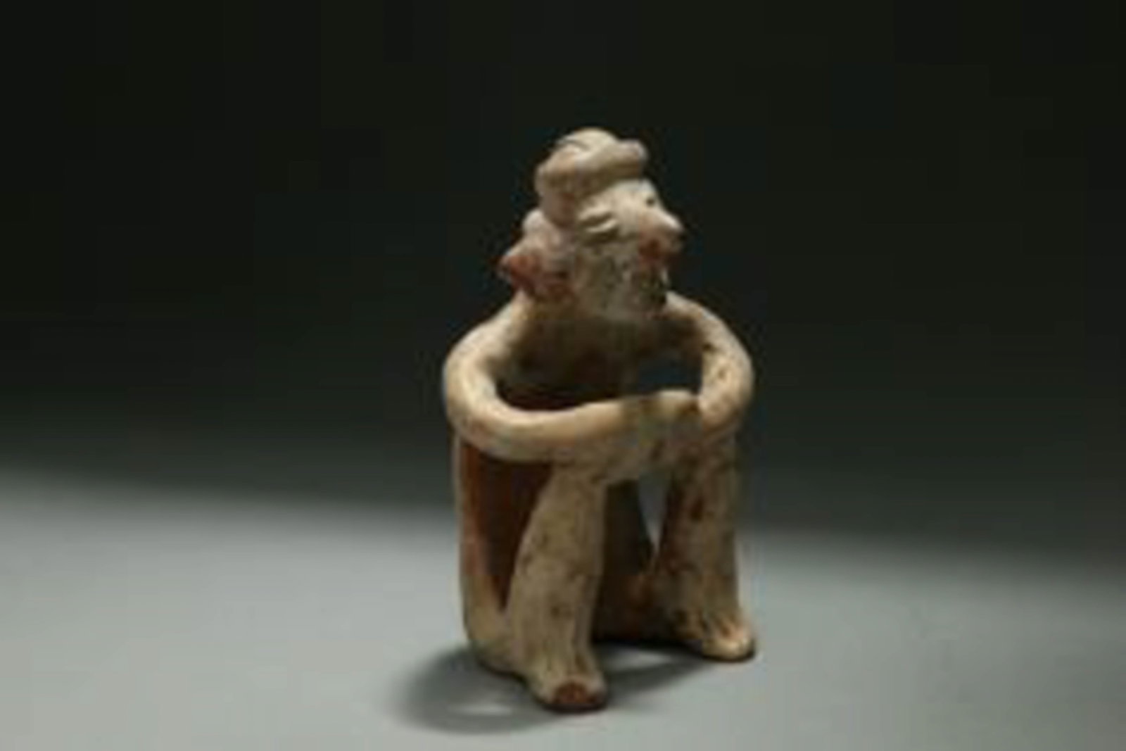 Pre-Columbian Nayarit Figure: A solid terracotta figure of a seating male, with nose and earrings. Wearing a hat. 5" H