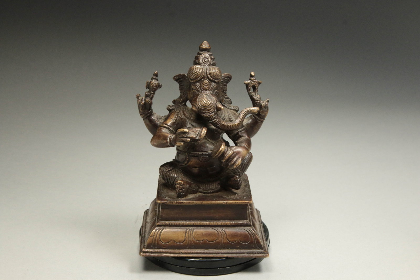 Bronze Statue of Lord Ganesha - India: A finely cast bronze statue of Lord Ganesha, the revered elephant-headed Hindu deity of wisdom, prosperity, and the remover of obstacles. 19th century. Ganesha is depicted seated in a relaxed meditati