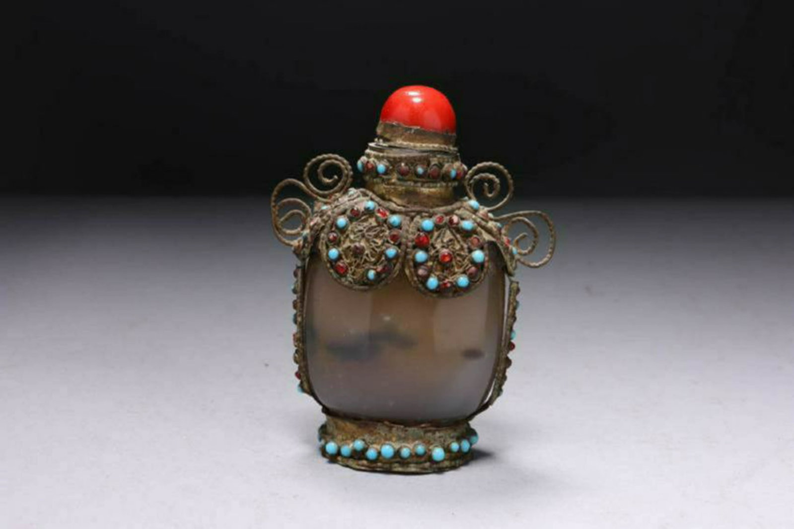 Tibetan Agate Snuff Bottle: Tibetan Agate Snuff Bottle, ca. 19th century, decorated with metal shoulder and base, filigree decoration with blue and red glass, coral glass stopper with spoon. Dimensions: 4" H; Weight: 6 oz. Prove
