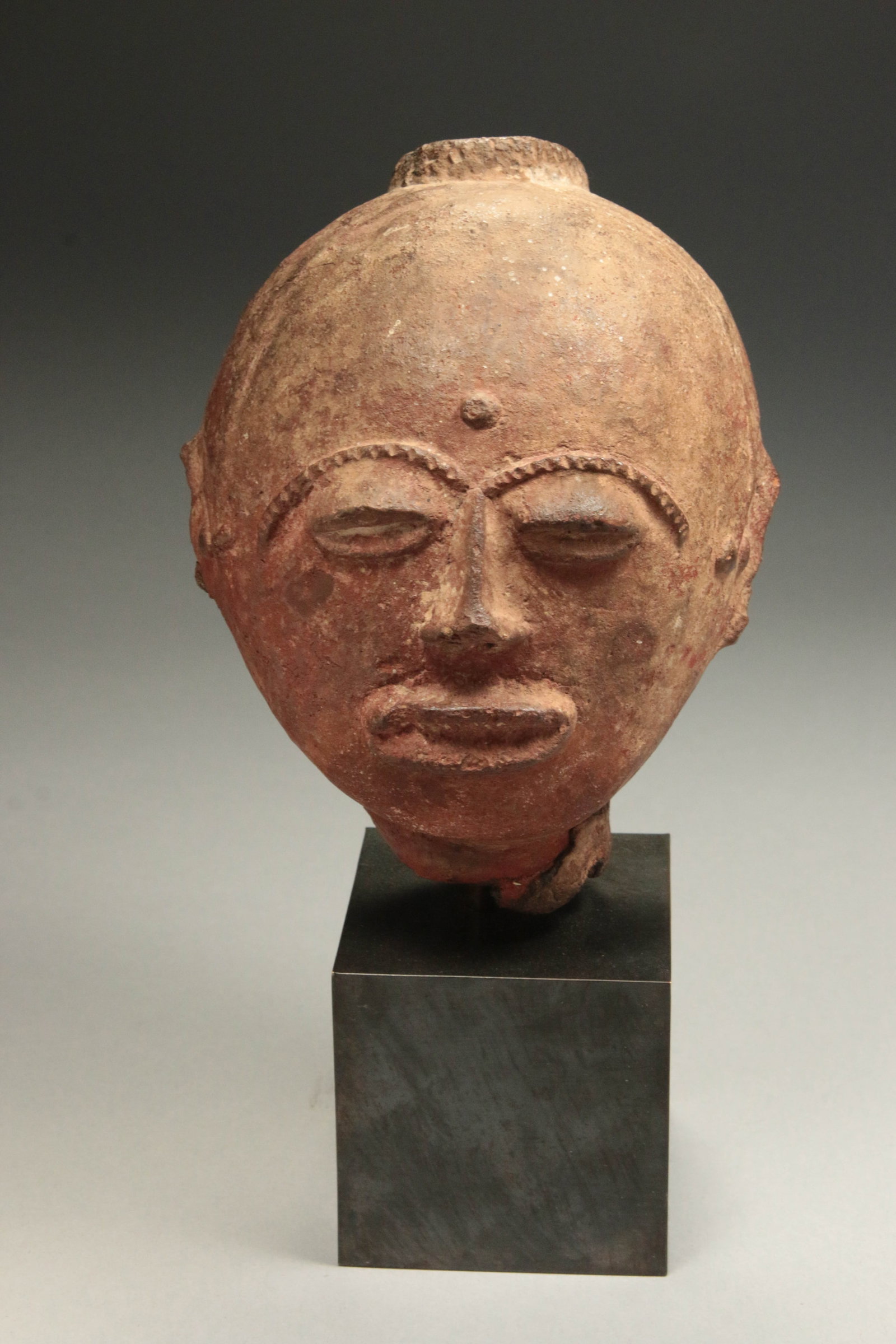 African Art Akan Terracotta Memorial Head: Akan terracotta memorial head, traditionally referred to as an nsodie. 7" H x 5" W. Display is included. These ceramic sculptures were created posthumously by artists of the Akan peoples from present-