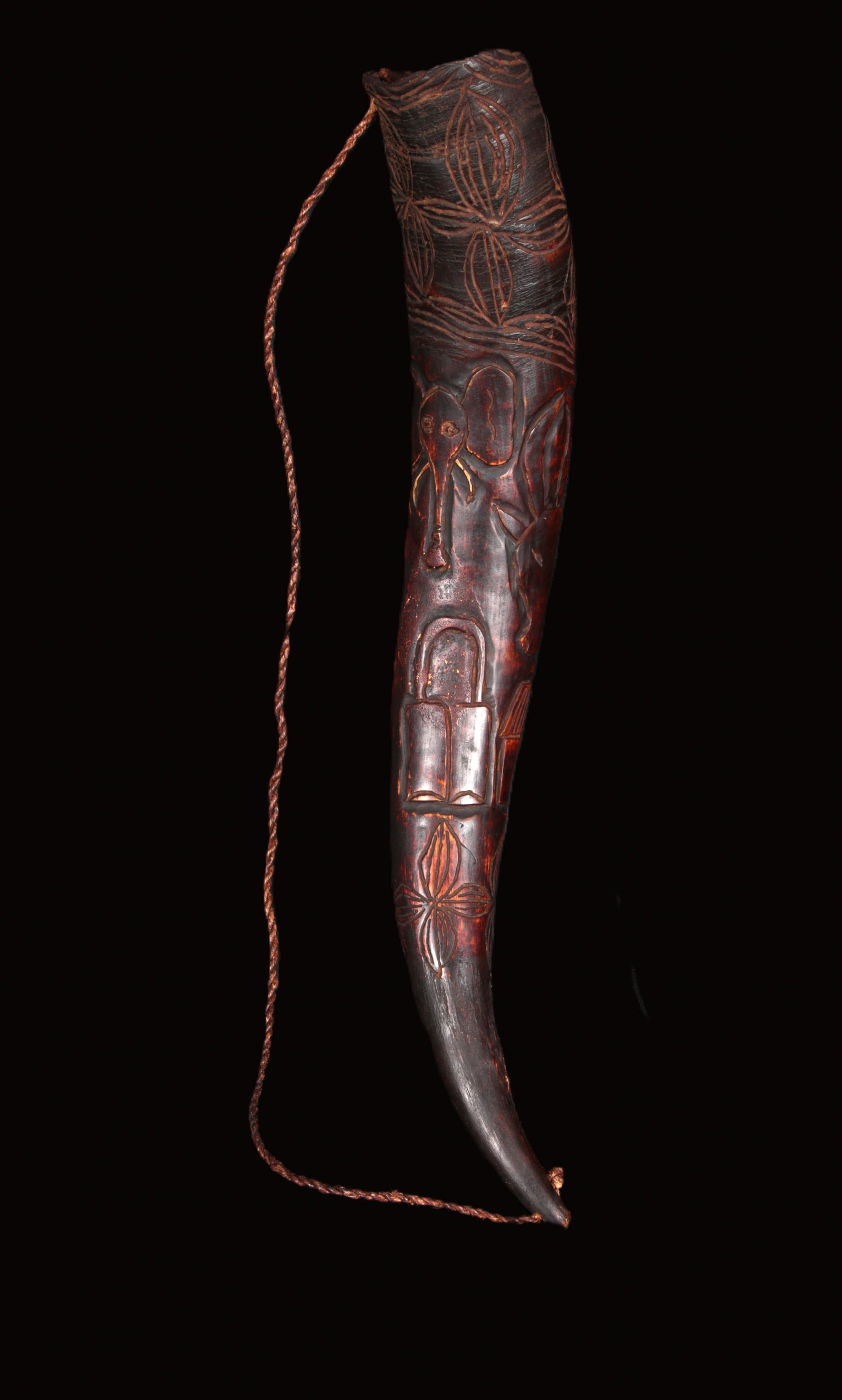 African Art Bamileke Trumpet: A carved hollowed cow horn side-blown trumpet with deep-relief motifs including and elephant. Woven cord attached for suspension. 19" L. Provenance: Ex. A. Njoya collection acquired from Leonard Kahan