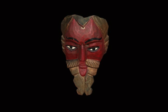Guatemalan Conquistador dance Mask: A hand-carved wood dance mask, red facial paing, prominent mustache, stylized beard, and molded hair. 10-1/2" H. This mask is used during the Baile de la Conquista (Dance of the Conquest), a