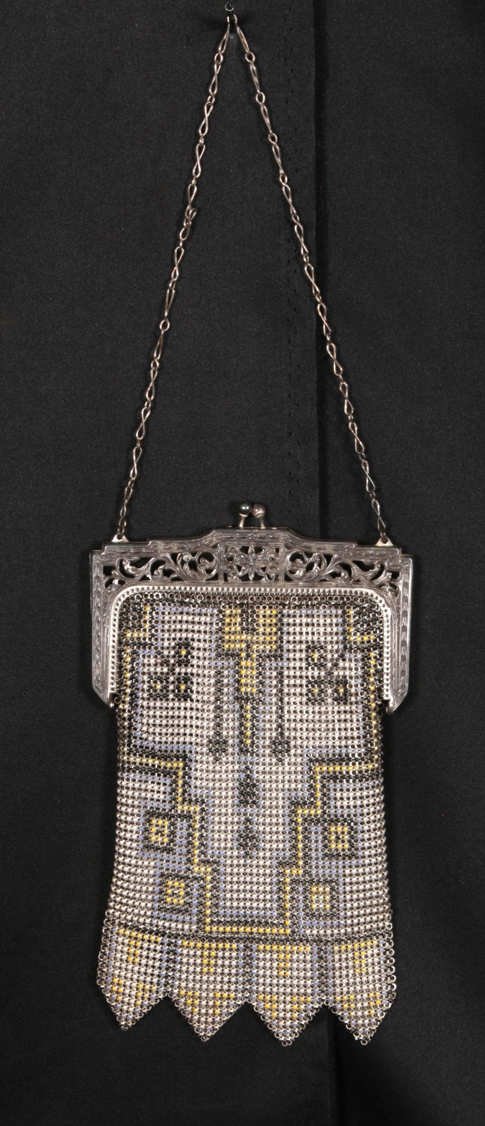 Art Deco Mesh Purse: A 1920's Art Deco enameled metal mesh flapper purse with geometric step motif, enamel colors. Outfitted with an ornately engraved, openwork filigree metal frame, a kiss-lock clasp closure, and a