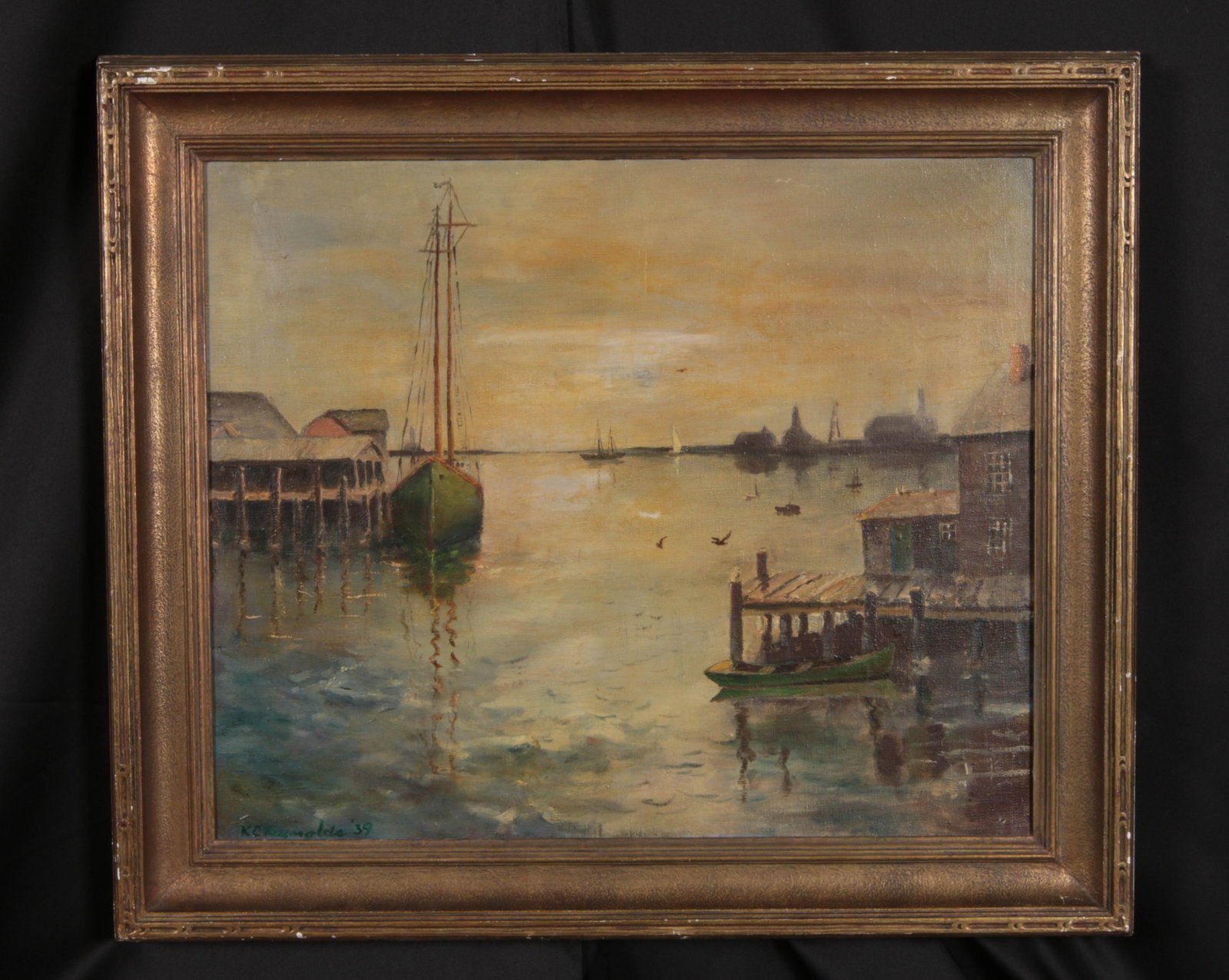 Oil on Canvas - Seascape Signed Attributed to R.C. Reynolds '39: An oil on canvas painting depicting a calm harbor at dusk or dawn, featuring a two-masted fishing schooner docked by weathered wooden piers, stilt buildings, and distant silhouettes of boats and docks