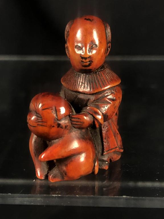 Netsuke Hand Wood Carved Child w/ Dog: Beautifully detailed hand carved wooden Japanese netsuke depicting a child with dog. Himotoshi on back. Measures: 1-1/2" x 1-1/8" x 1/2".