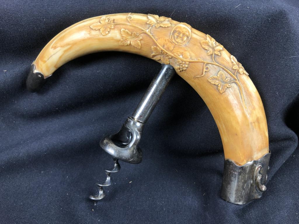 XCarved Boar Tusk Corkscrew w. Silver Caps c 1880: This rare hand carved boar's tusk has silver caps and screw. The scrimshaw engravings on the tusk feature figure surrounded by grape vines. 7-1/2" wide x 5-1/2" high c.1880?