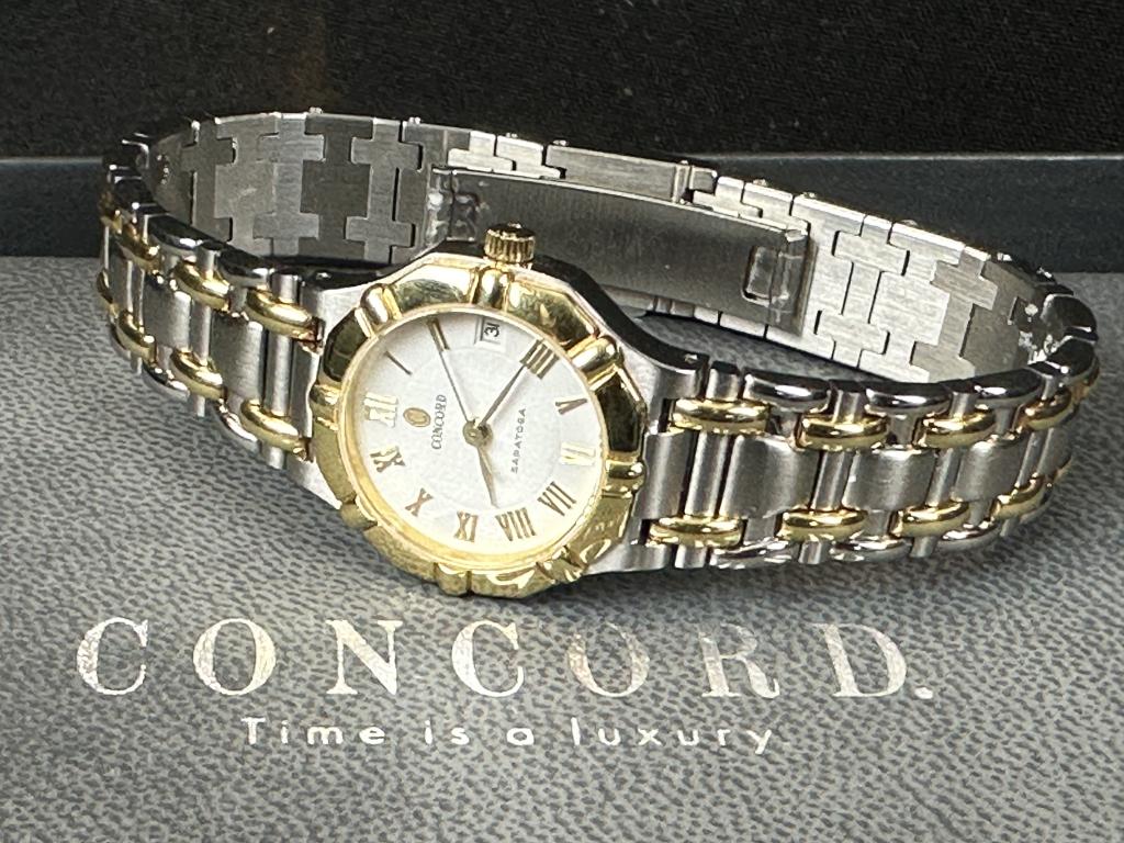 Concord Saratoga Watch 18K & Stainless: This Concord Saratoga watch is in excellent condition. The 34mm diameter case houses a quartz movement, while the white dial features roman numeral markers and a date indicator. It comes on a two-tone