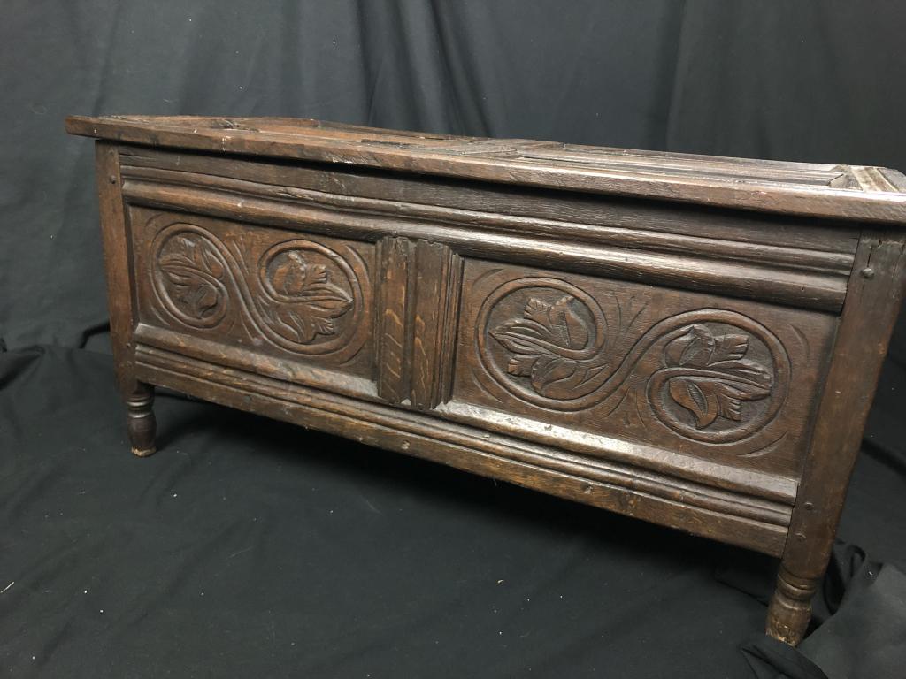Primitive Carved Gothic Wooden Chest Trunk: Antique carved chest made of rich dark wood with hand carved leaf motif and cylindrical feet. Sturdy with fine detail. 4 panel hinged top. Use for storage, seating and decor. Solid. Measures: 38-3/4"