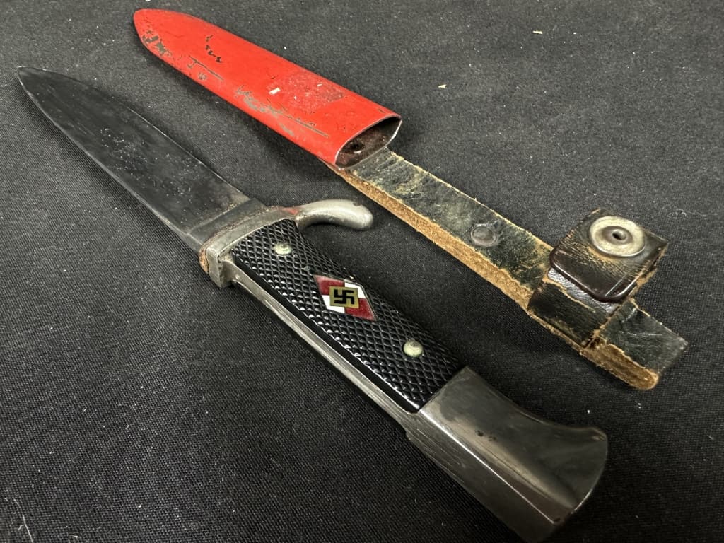 WWII German Hitler Youth Knife & Scabbard: This Hitler Youth knife and case is shaped like a military bayonet and bears the emblem of the Hitler Youth. Marked: "RZM M7/13 Arthur Schüttelhofer & Co., Solingen-Wald." Measures 10" long. Begi