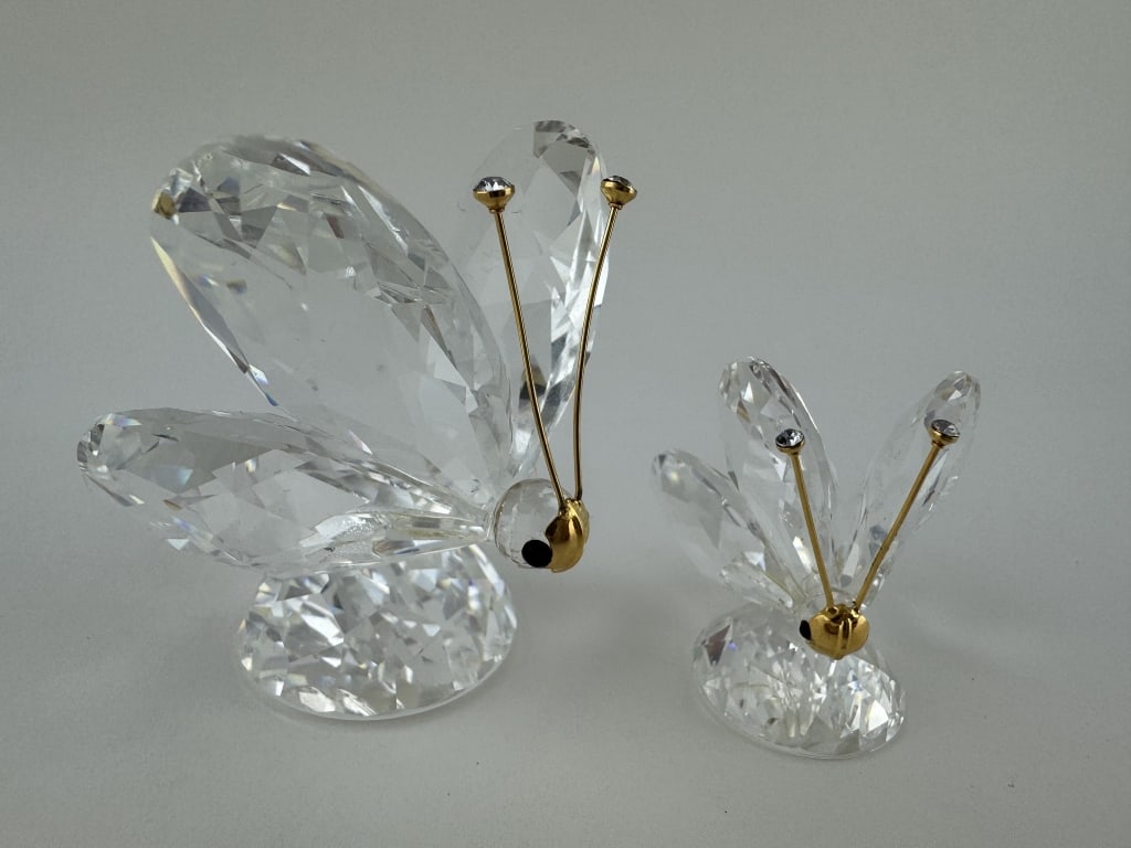 Pair of Swarovski Crystal Butterflies 2 Sizes: Pair of faceted Swarovski crystal butterfly figurines with gold metal accents. 2 sizes. Measures: 2-1/4" x 1-3/4" x 2" & 1-1/2" x 1-1/4" x 1-1/2".