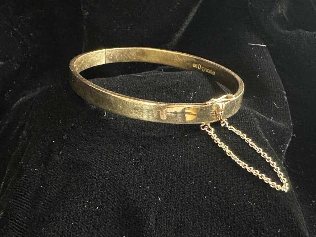 18k Yellow Gold Hinged Bangle w/Safety Chain: 18K yellow gold hinged bangle with safety chain link . Weighs 9.9 DWT. Approx. 7-2/8ths inch inside measurement.