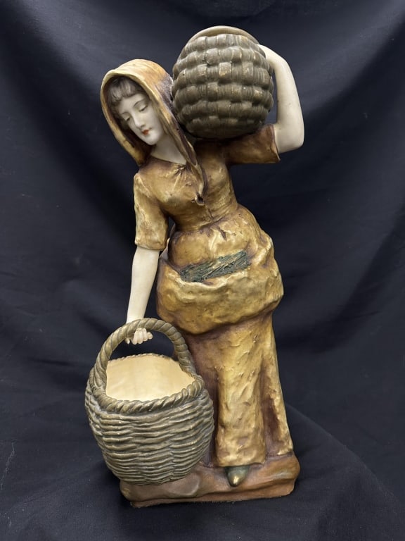 Lg. Amphora Austrian Maiden Porcelain Statue: A large antique Austrian Amphora statue depicting a young maiden carrying two baskets. The piece is stamped "Amphora" & "Austria" on the bottom, as well as a crown mark and numbers. Measures: 8-3/4" W