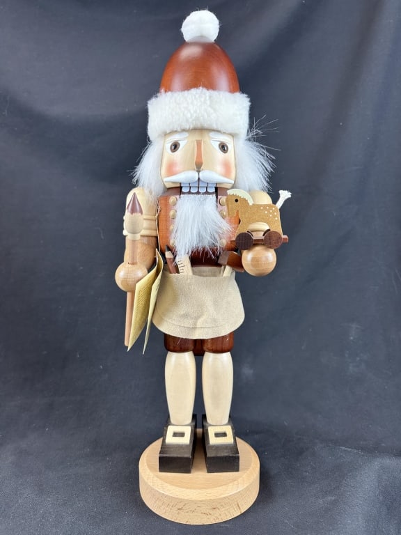 Santa's Workshop Nutcracker Christian Ulbricht: A "Santa's Workshop" Nutcracker handcrafted in Germany by the Christian Ulbricht company. This collectible nutcracker features the "natural" theme with wooden clothes and hat, and wears a cloth apron