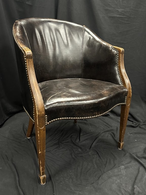 English Barrel Back Club Chair Dark Br. Leather: A vintage English-style dark brown leather club chair/ library chair / armchair, featuring a barrel back design with nail head trim. The piece has an upholstered mahogany stained frame with carved arm