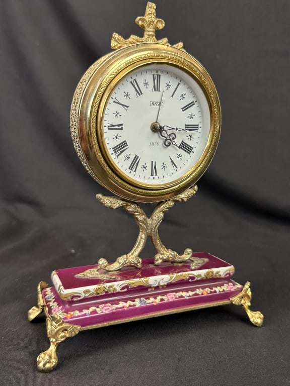 Porcelain Gilt Ormolu Wind-Up Alarm Clock Ritz ACF: A vintage Ritz ACF wind-up alarm clock, featuring a clock body with highly detailed design patterns and a roman numeral clock face. The piece has a hand-painted porcelain base over a metal plate with