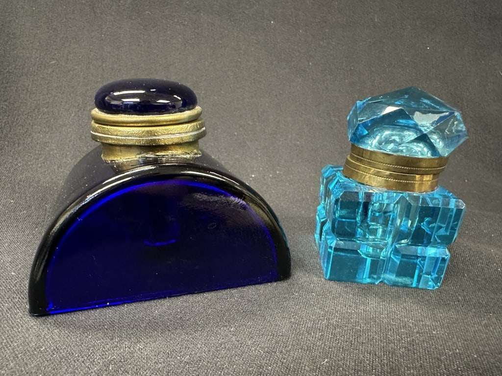 2 Crystal Inkwells: Cobalt Blue & Turquoise: A vintage pair of lidded inkwells, each with a contrasting shade of blue. The cut crystal inkwell features a turquoise color and a faceted top, while the other has a domed semicircle shape with cobalt