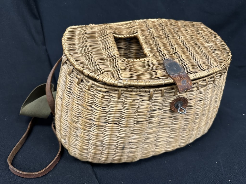 Vintage Leather Woven Wicker Fishing Creel Basket: A vintage woven wicker creel, a traditional fishing basket used by anglers to safely carry and store fish. The lid features a viewing window that provides access without fully opening the lid, and the