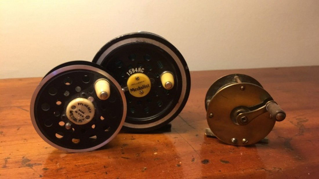 Lot of 2 Fly Reels and Spool: Lot of 2 Fly Reels and Spool including one Pfleuger Medalist 3 1/2" remaining in very good condition, one Pfleuger spare spool 2 1/2" in fair condition and one antique brass 2 3/4" with wood handle re
