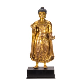 A VERY RARE BRONZE-GILT STANDING BUDDHA