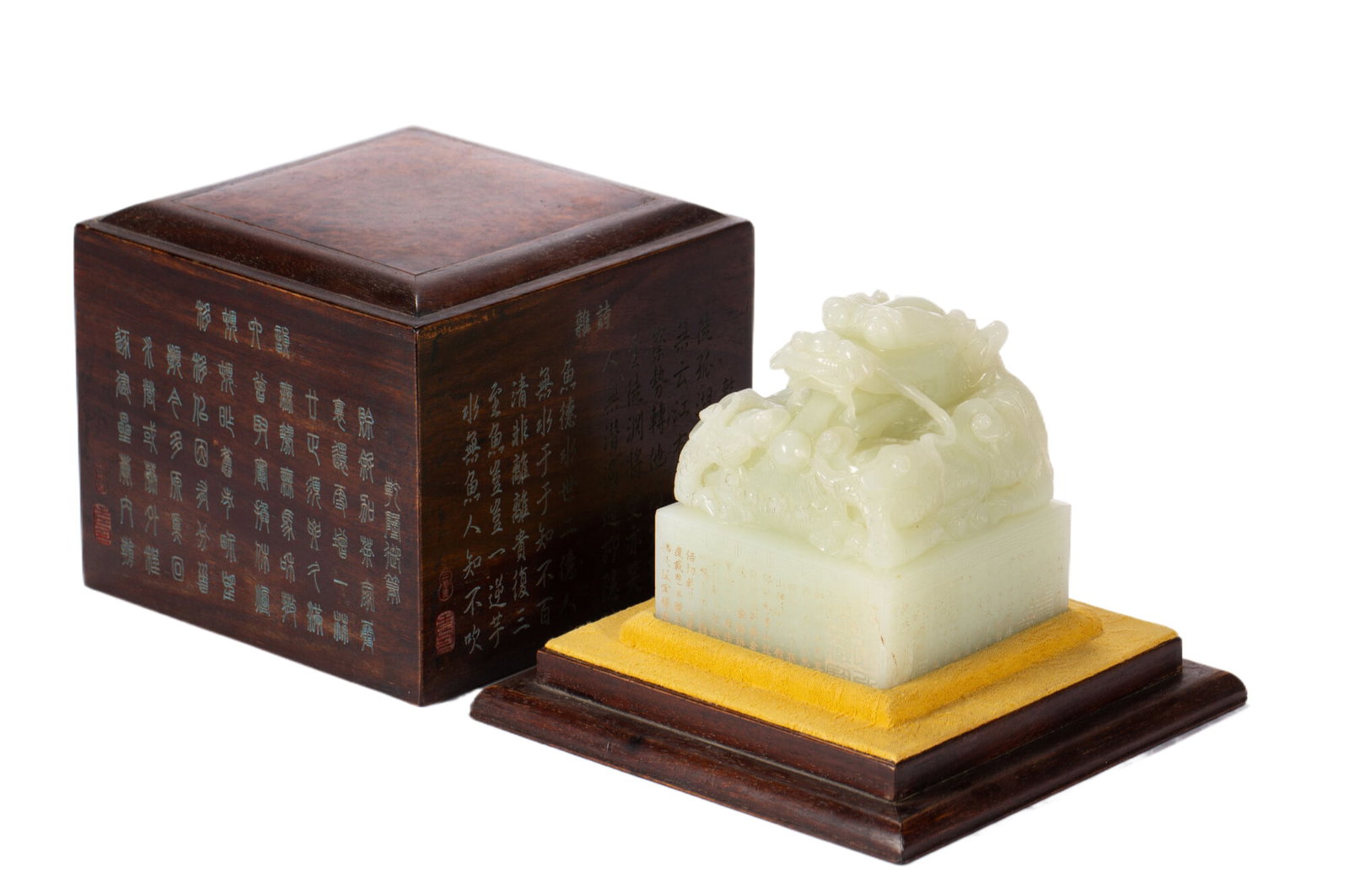 A CARVED WHITE JADE DRAGON SEAL: A CARVED WHITE JADE DRAGON SEAL Of squared shape, surmounted with a coiled dragon as finial, the stone is of white tone, with an inscribed wooden box with cover. DIMENSION: L. 9 cm. W. 9 cm. H. 11