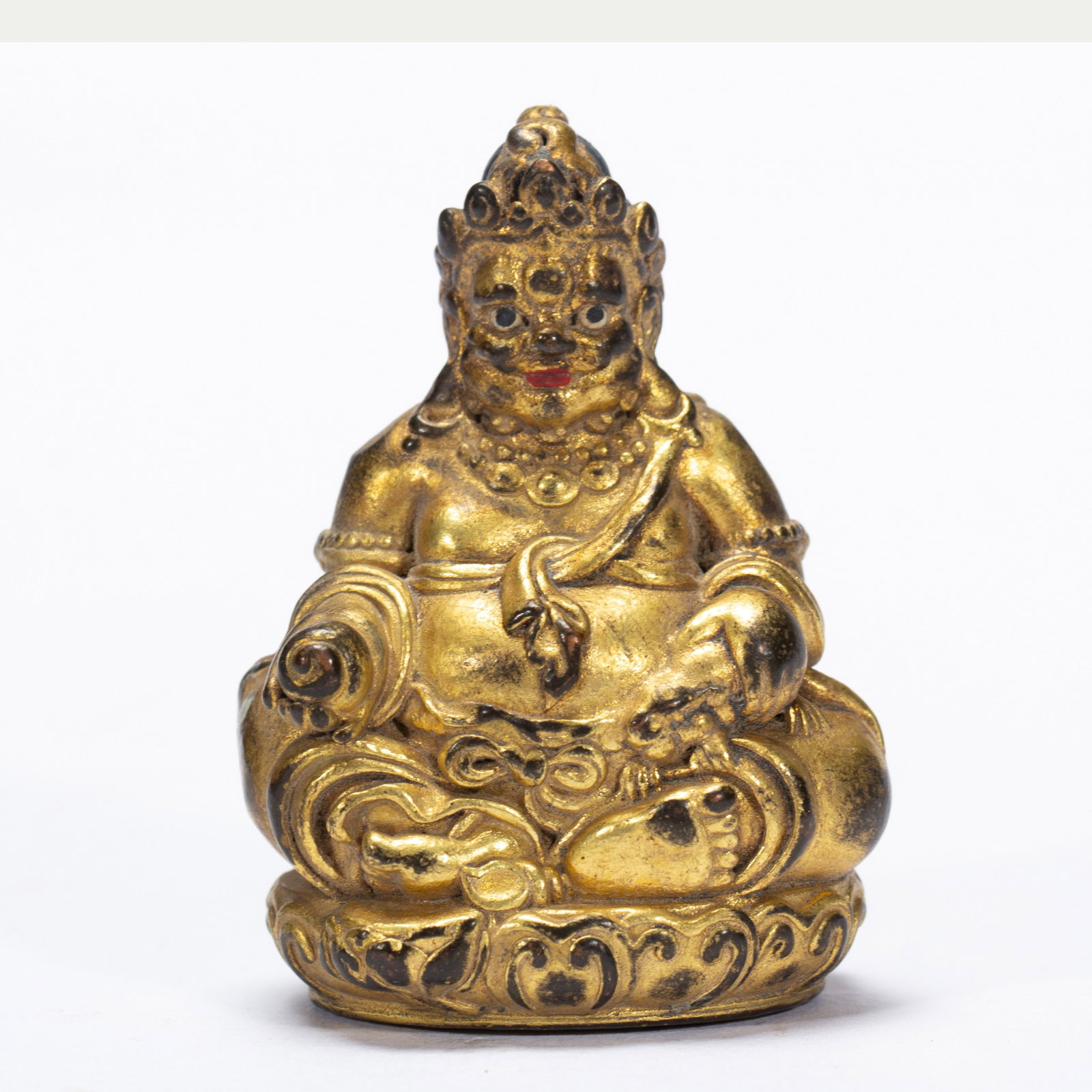 A BRONZE-GILT FIGURE OF JAMBHLA: A BRONZE-GILT FIGURE OF JAMBHLA Seated in lalitasana on a lotus stand, his right hand held in vitarkamudra and his left holding a mongoose, dressed in a billowing dhoti and adorned with beaded jewelry