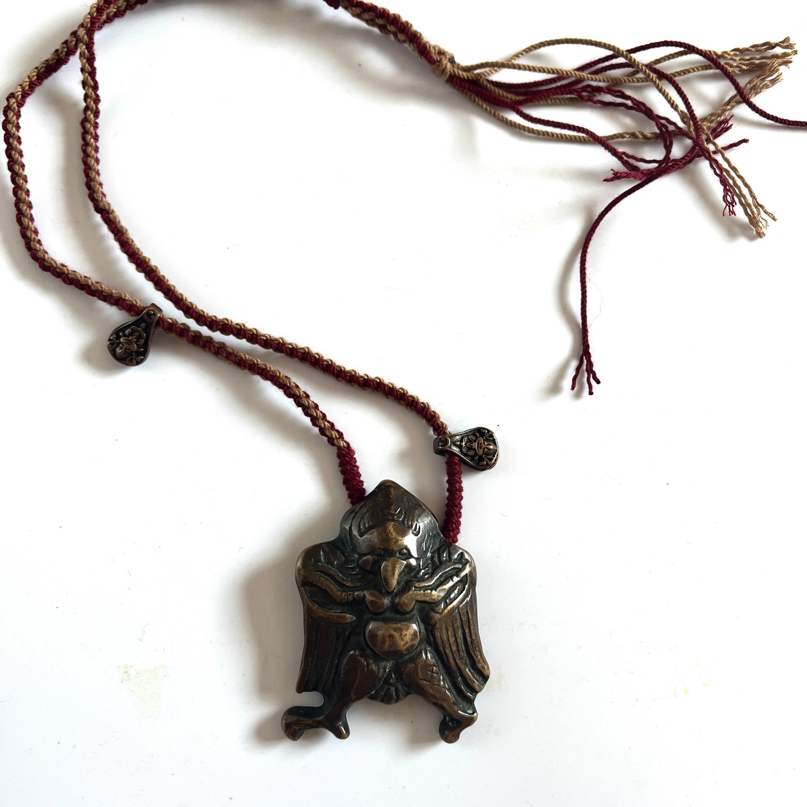 A BRONZE GARUDA NECKLACE: A BRONZE GARUDA NECKLACE The garuda is a mythological bird of India and Tibetan folklore. He wages continual warfare against the nagas or serpents. Thus he is considered to be a protection against