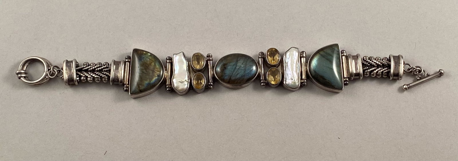 Sterling Bracelet w/Bezel Set Semi Precious Stones: Sterling silver bracelet with bezel set labradorite, mother of pearl and topaz?. Marked 925. 8 inches long. Total weight 53.6 grams DG