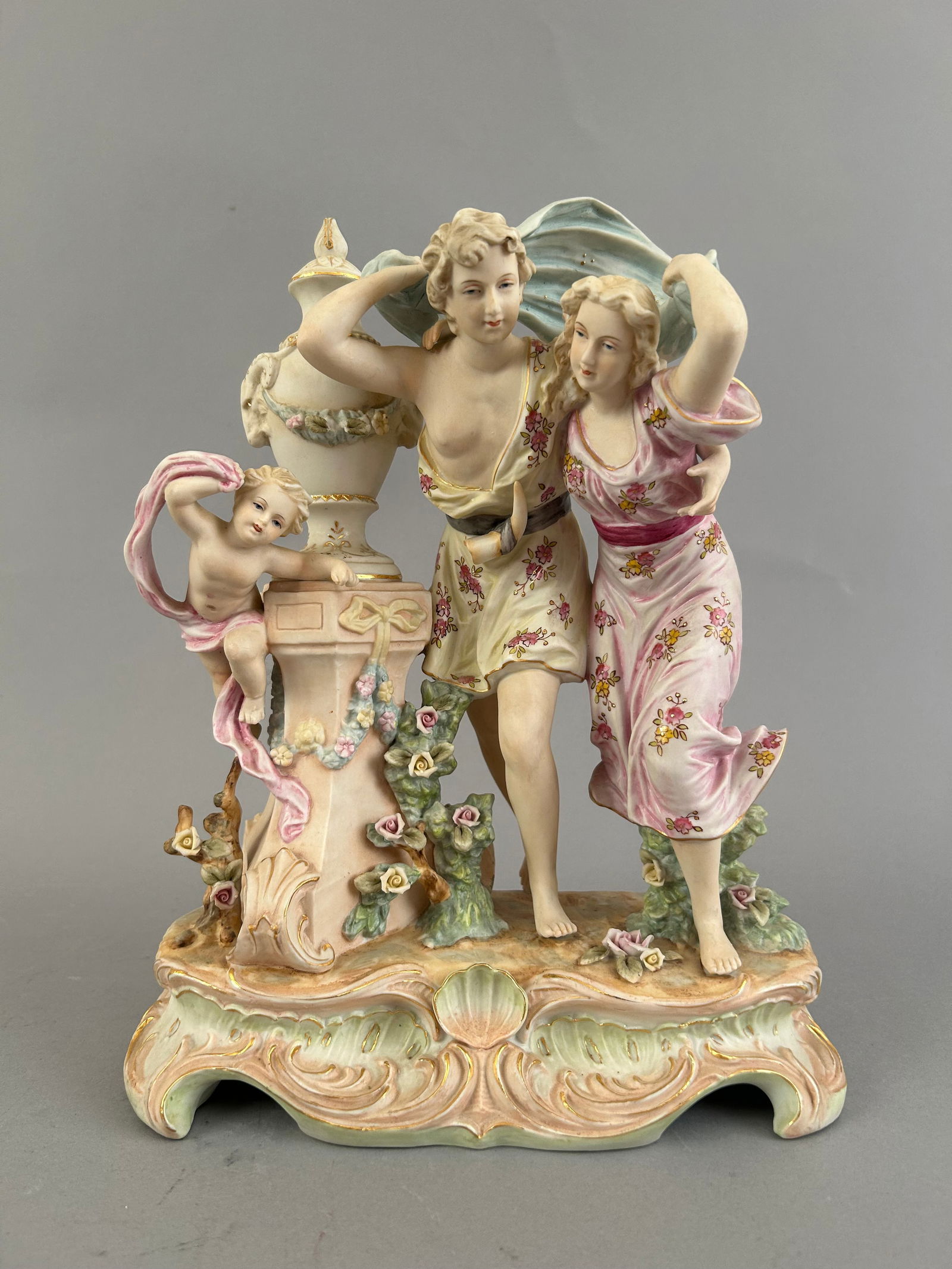 Bisque Porcelain Statue With A Pair Of Lovers Running: Bisque porcelain statue with a pair of lovers running with a Cupid or cherub. Marked on the bottom.