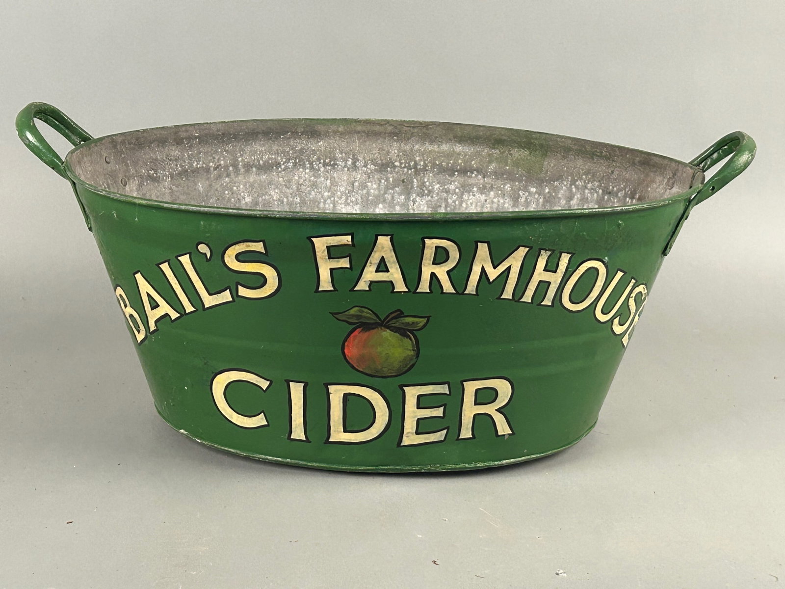 Vintage Bail's Farmhouse Cider Advertising Pail: Vintage "Bails Farmhouse Cider" advertising pail. Large wash pail with lettering and picture of Apple with green background. 20th century. 23.5" x 15" x 9.5"Provenance: Robert and Jane Cottingham Coll