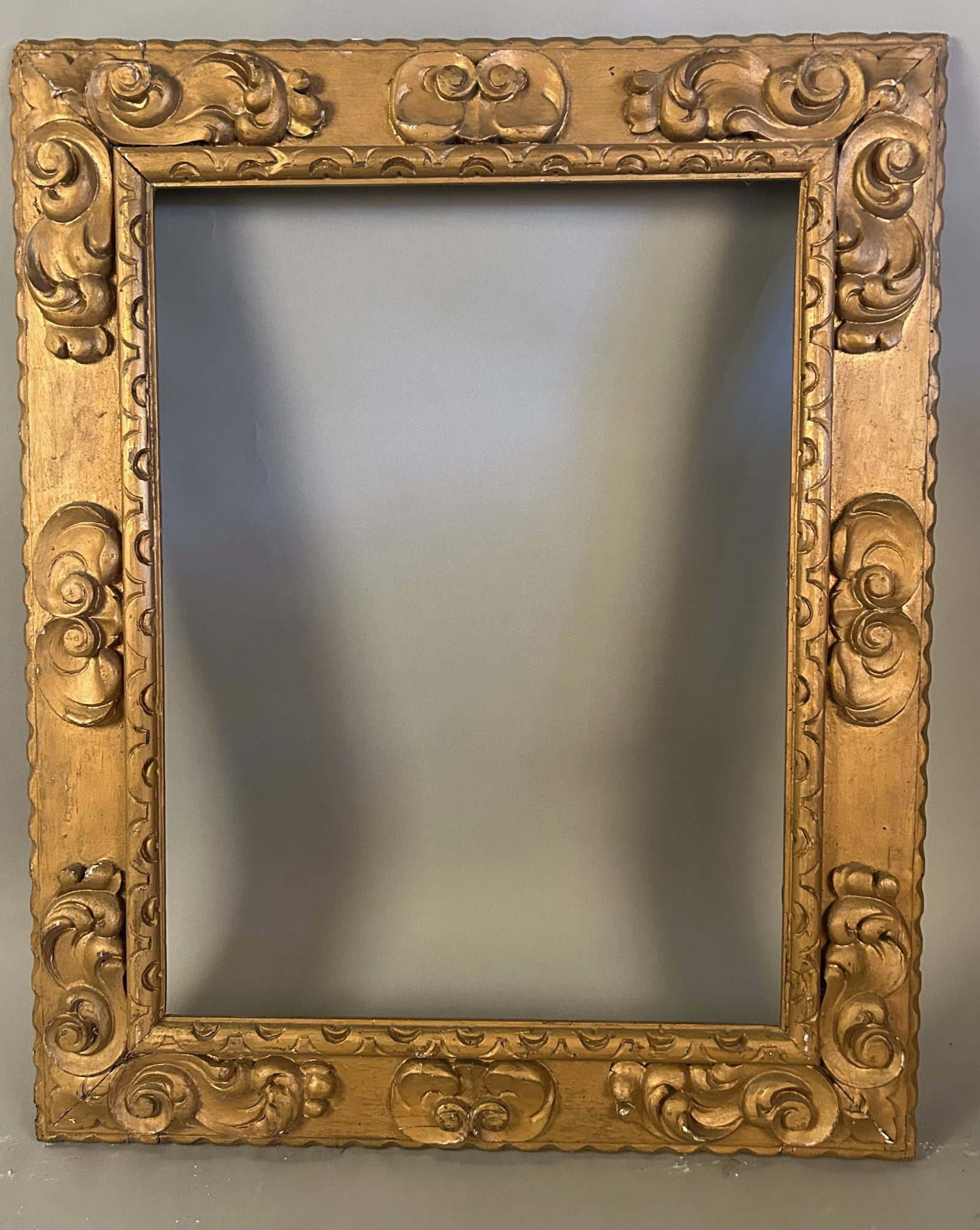 Antique Gold Frame – High Relief Scroll & Cartouche Decoration: Antique Gold Frame – High Relief Scroll & Cartouche DecorationDecorative antique giltwood picture frame featuring bold, high-relief scrolling acanthus and cartouche motifs at the corners and midpoin