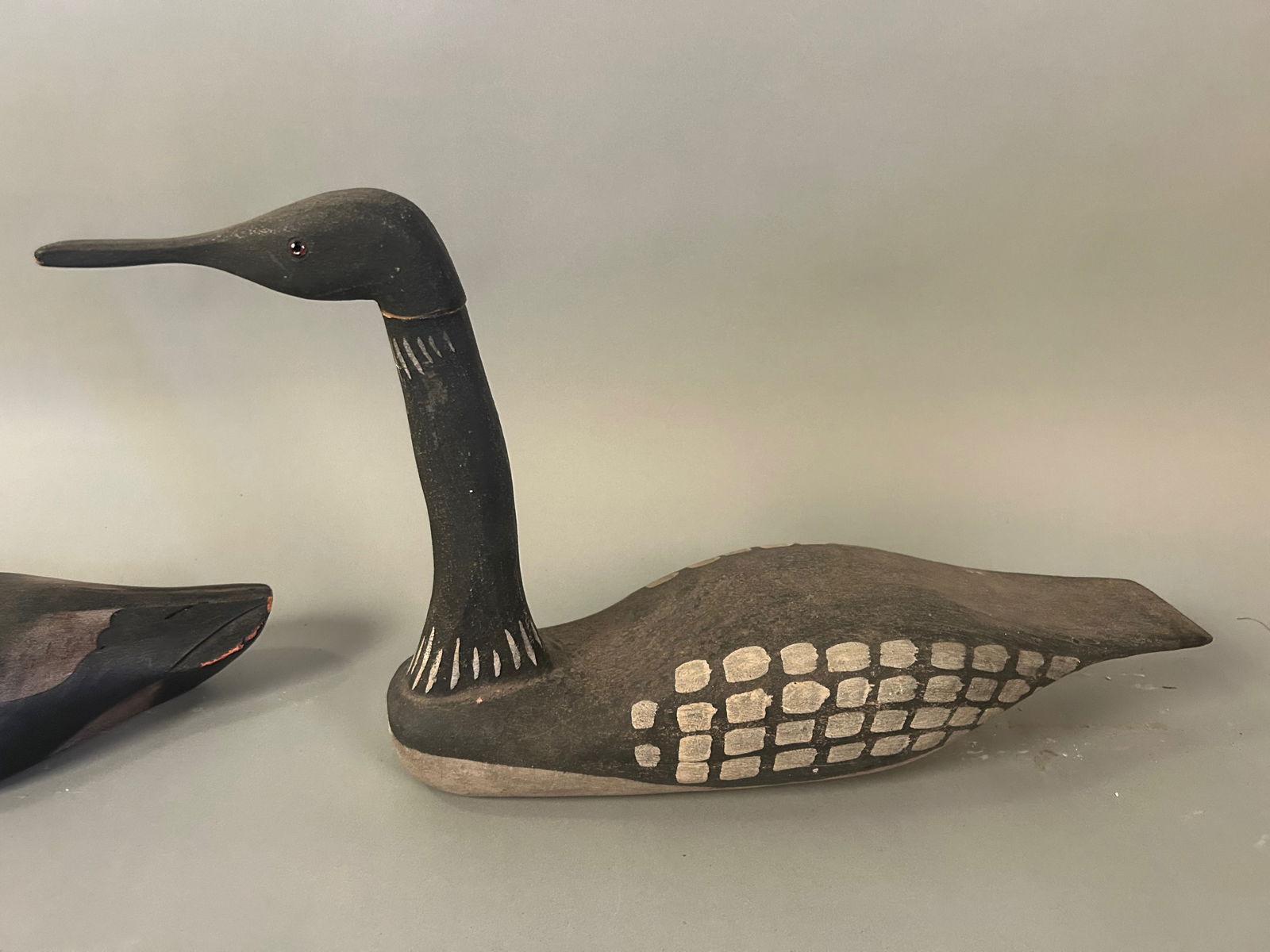 2 Hand-Carved Wooden Decoys Loon and Duck: 2 Hand-Carved Wooden Duck DecoysTwo hand-carved wooden duck decoys, including one long-necked loon-form example by /richard Morgan and one compact duck in resting pose. Painted surfaces with simple