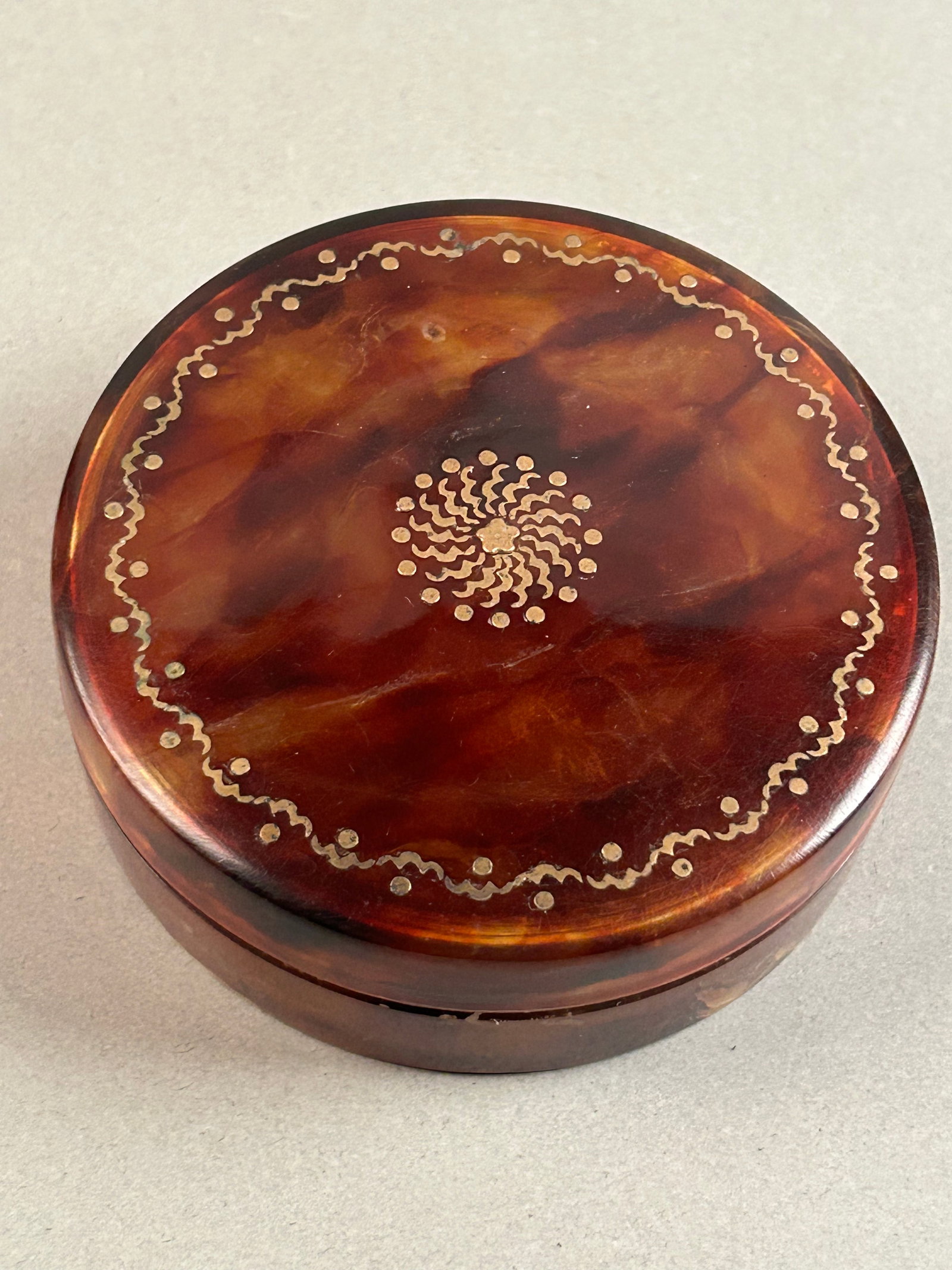 Italian, Probably Naples, 18th-Century Tortoiseshell and Gold Piqué Snuff Box.: Circular tortoiseshell box decorated throughout the lid in elaborate gold piqué with a radiating sunburst of scrolling motifs and pellets within a continuous undulating dotted border.