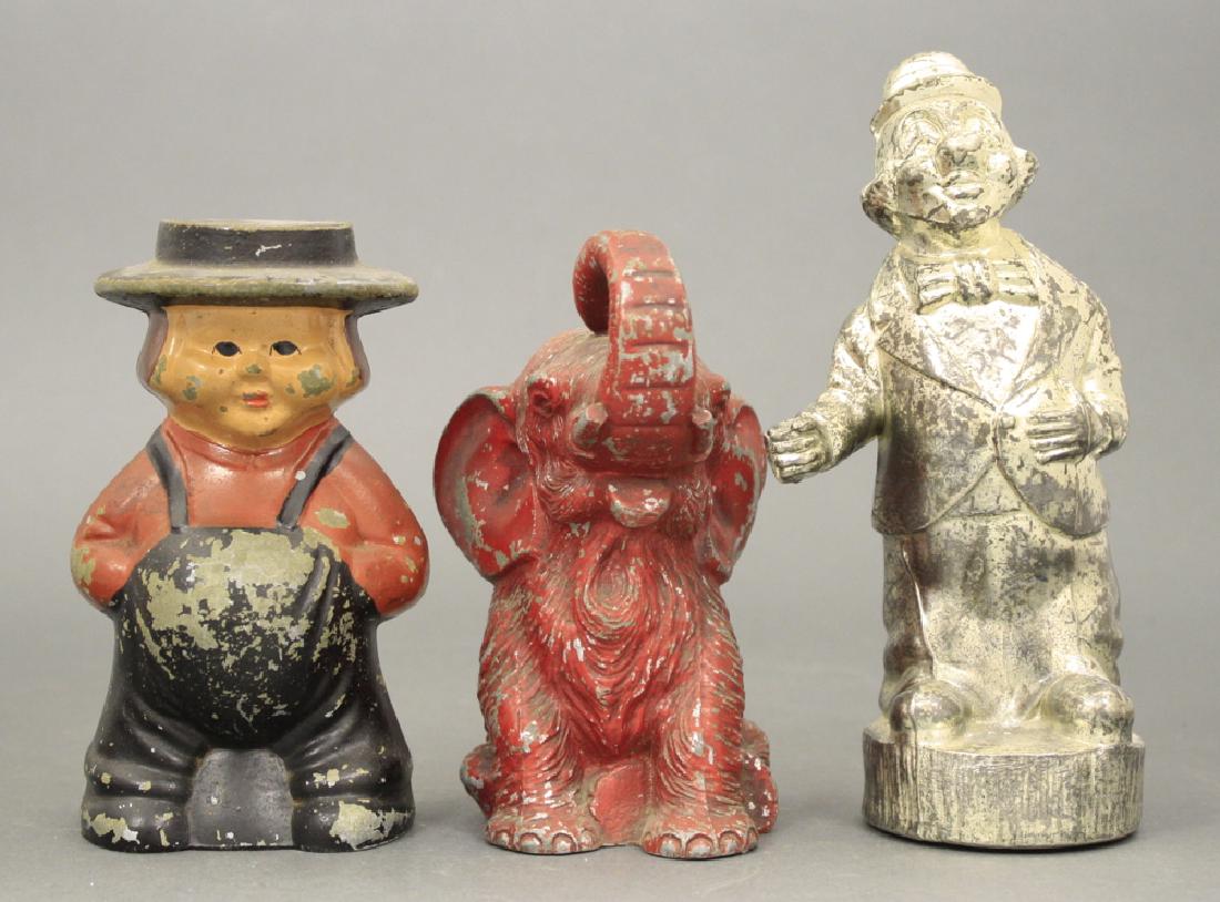 Lot: Three Banks: Included Amish Boy (John Wright, Aluminum circa 1970's), Seated Elephant (Vanio, White Metal circa 1930's) and Man Wearing Hat. Very Good or Better Condition.