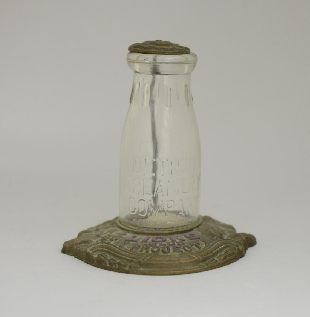 Lions Club Project Still Bank: Detroit Creamery Company. A Glass Bottle with a Cast Iron top (Coin Slot) and base. 6" Tall. Fine Condition.