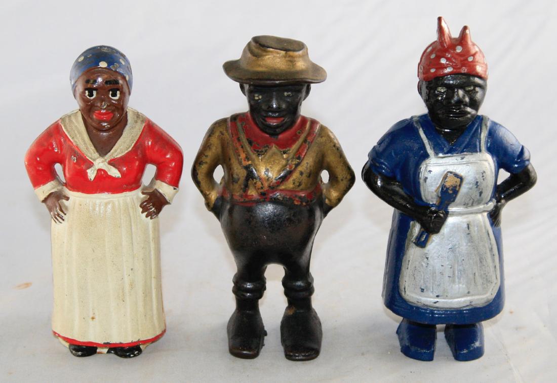 Three Figural Cast Iron Banks: Mammy Hands on Hips: Made by Hubley circa 1920's. 5 1/4" T. Sharecropper: Made by A. C. Williams circa 1900's. 5 1/2" T. Mammy with Spoon: Made by A. C. Williams circa 1900's. 5 7/8" T. All made of Ca
