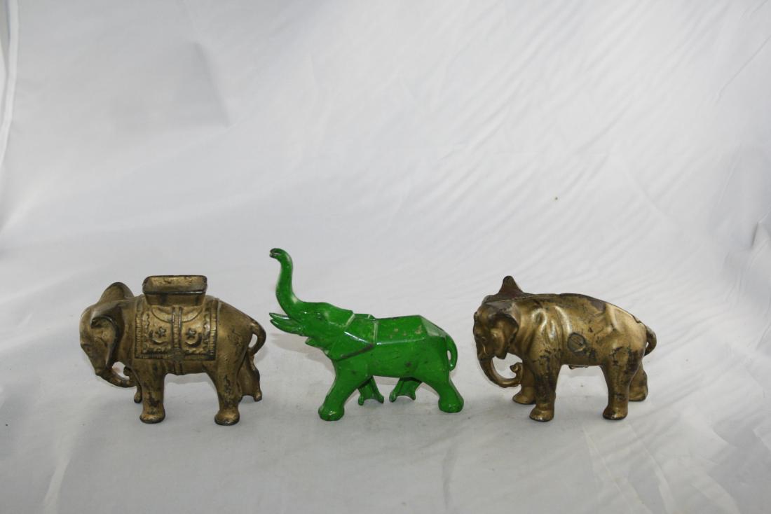 Three Elephant Cast Iron Still Banks: Elephant with Tuck Trunk: Made by Arcade circa 1910's. 2 3/4" L. Art Deco Elephant: Made in America. Elephant with Howdah, Small: Made by A. C. Williams circa 1910's. 3" L. All made of Cast Iron. Fine
