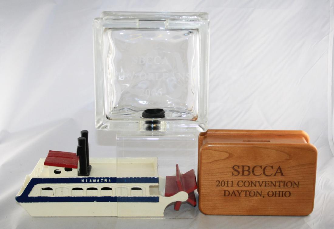SBCCA 2006, 2011 & Hiawatha Still Banks: SBCCA 2006 Glass Cube 5.75" T. SBCCA 2011 Wooden Box 6" W. Hiawatha Cast Iron River Boat 9.5" L. Excellent to Pristine Condition.