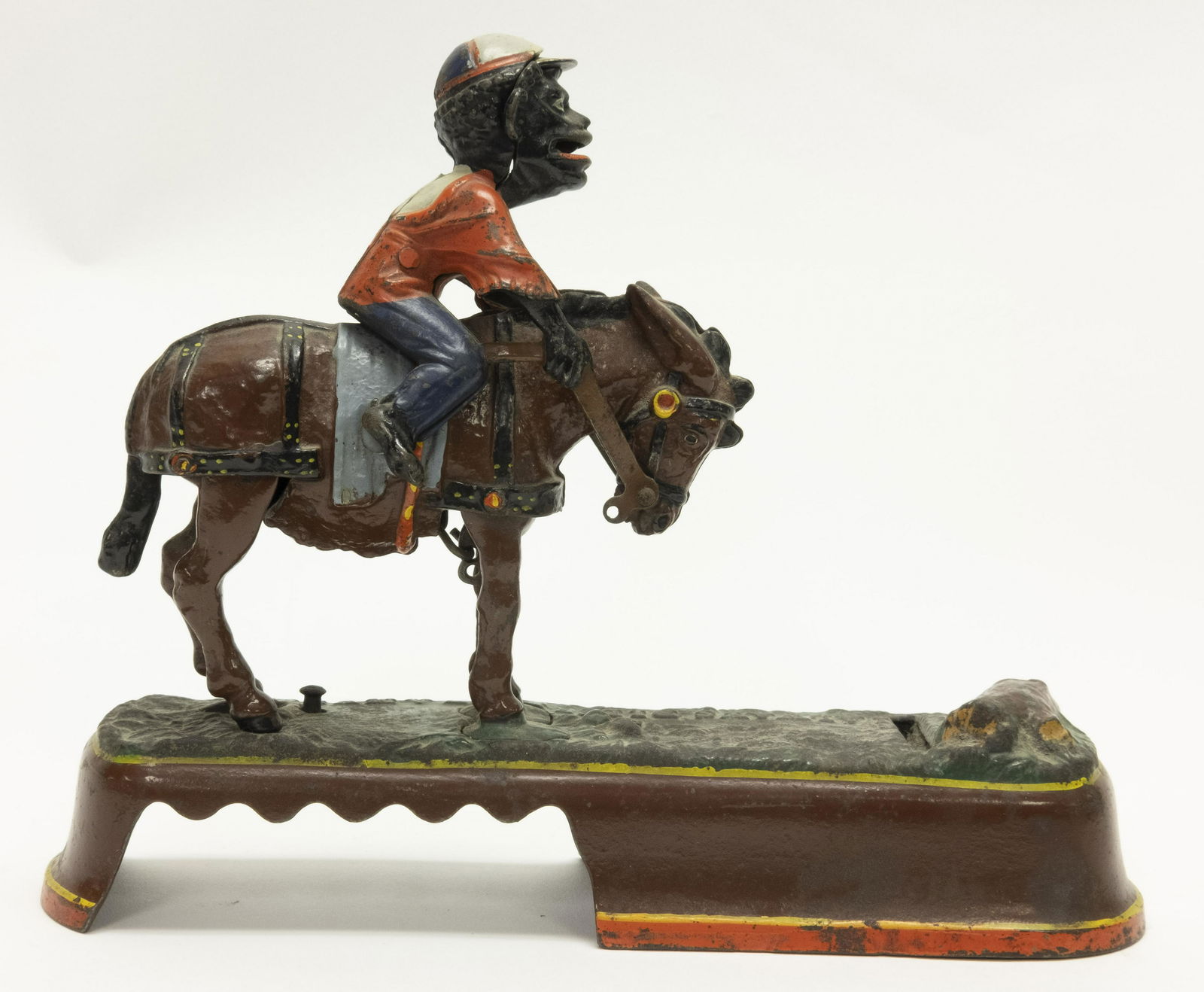 I Always did Spise a Mule, Jockey Iron Bank: Made by J. & E. Stevens of Connecticut circa 1879. Place a coin in the Jockey's mouth. Press the lever and the mule throws the jockey. The coin is deposited into the tree stump. Made of Cast Iron. Ver