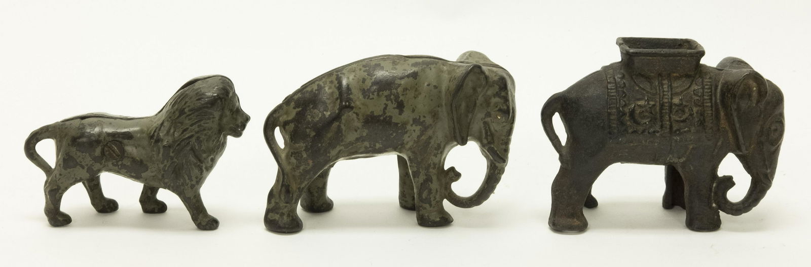Three Animal Themed Cast Iron Still Banks: Included: Lion, Elephant Tucked Trunk and Elephant with Howdah. Made of Cast Iron. Fair to Good Condition.