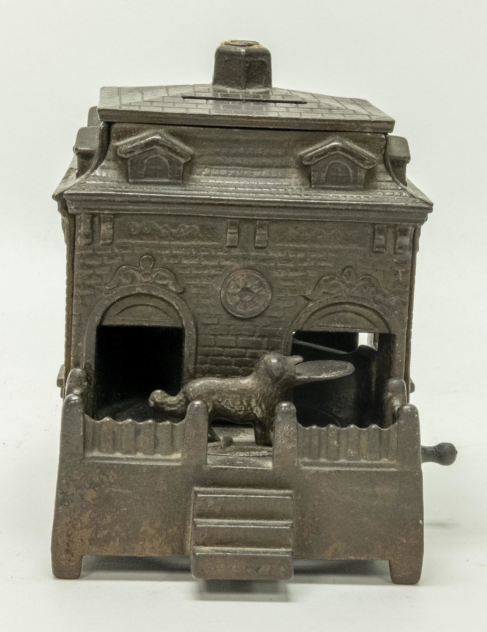 Dog on Turntable Iron Mechanical Bank: Made by H. L. Judd of Connecticut circa 1895. Turn the crank and the dog enters the building and deposits the coin. Made of Cast Iron. Fine Condition.