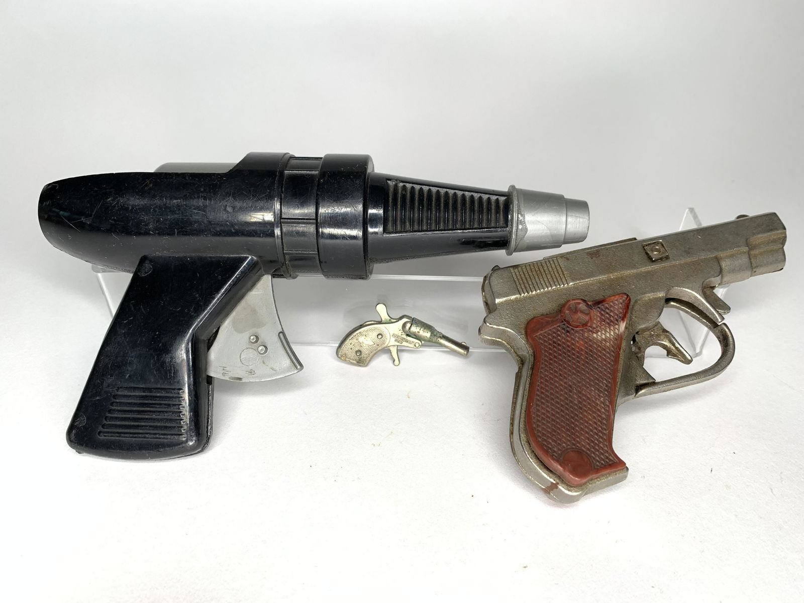 Assortment of Cap Guns: American. Circa 1930. Presto cast iron gun, small cast iron gun and space laser gun. Measuring from 2 inches to 8 inches in length. Very Good Condition.